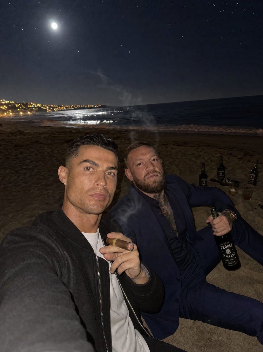 Dwaj mężczyźni na plaży nocą, księżyc nad wodą